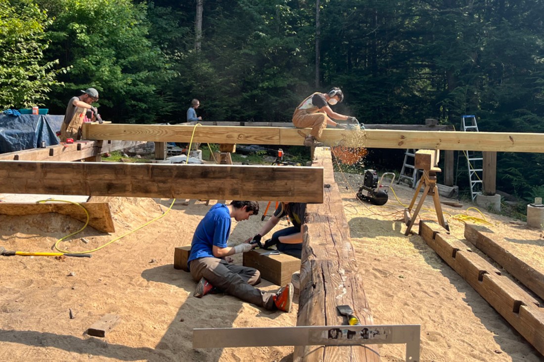 Several people building a wooden frame of the lodge in the summer.