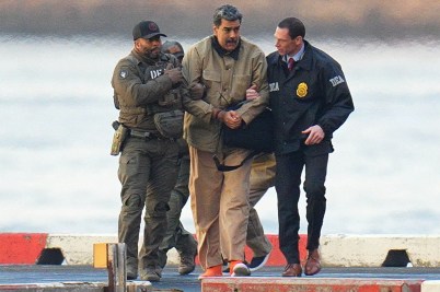 Nicolás Maduro is escorted by two men in military uniform. There is water in the background.