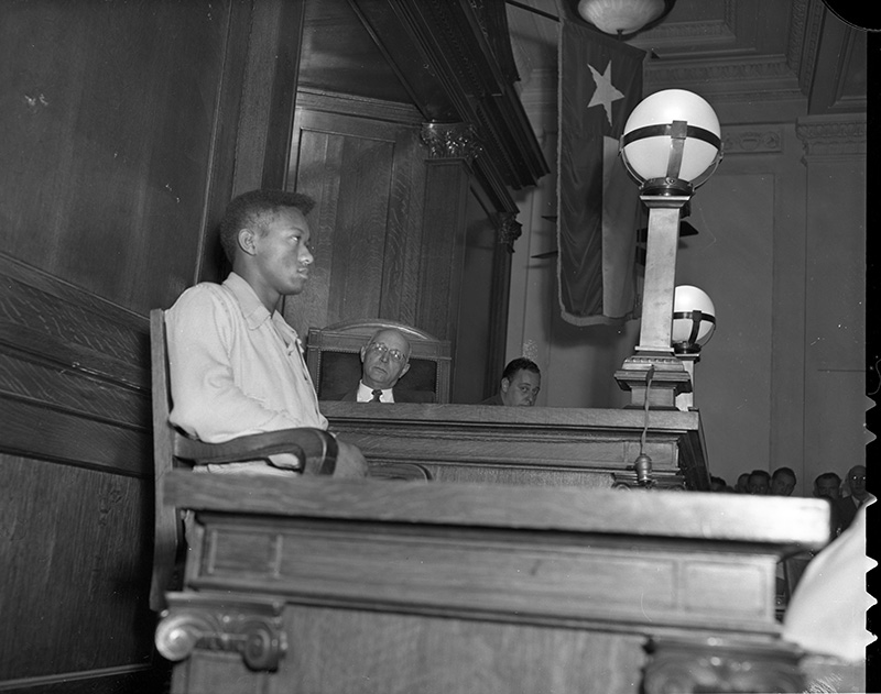 Black and white historical photo of Tommy Lee Walker sitting in court. 