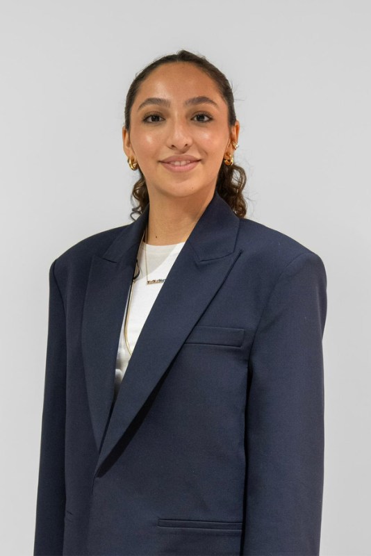 A woman wearing a navy blazer and white t-shirt
