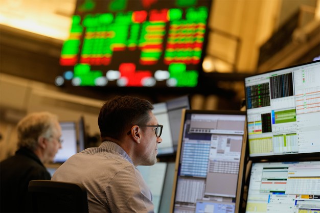 Man with glasses looks at multiple computer screens