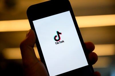 A person's hand holding a phone open to a screen displaying the TikTok logo.