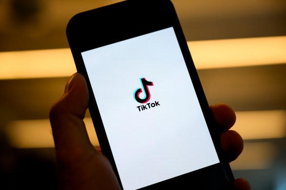 A person's hand holding a phone open to a screen displaying the TikTok logo.