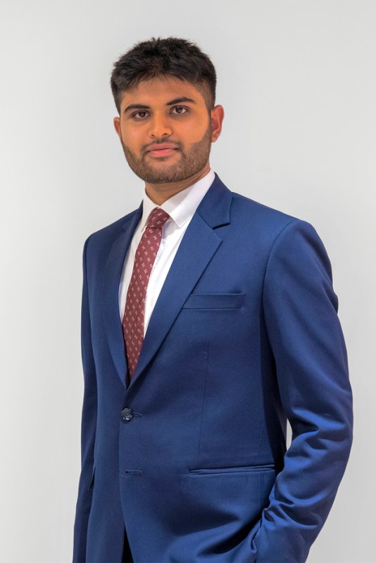 A bearded man wearing a blue suit and red tie