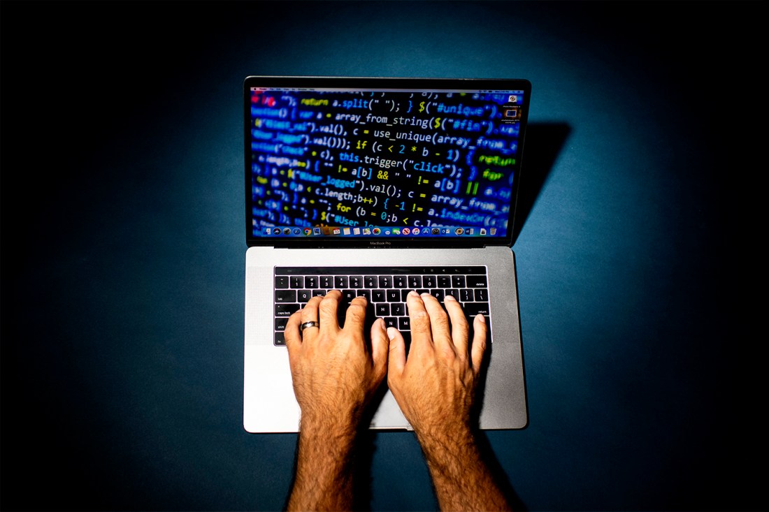 A person whose hands alone are visible at work on a laptop.