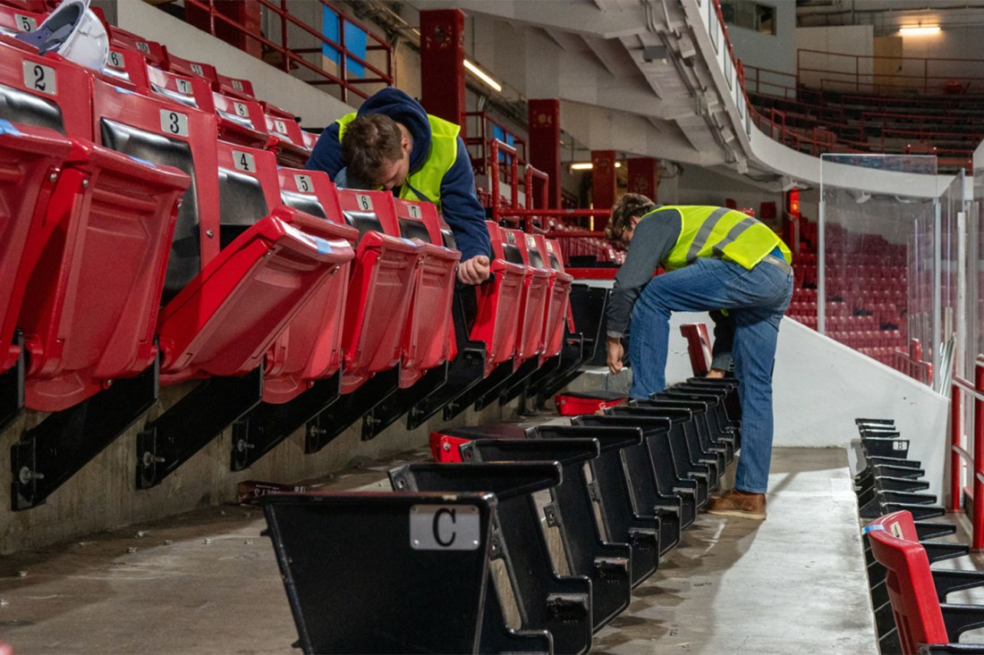 Workers in high vis vests removing seats from Matthews Arena.