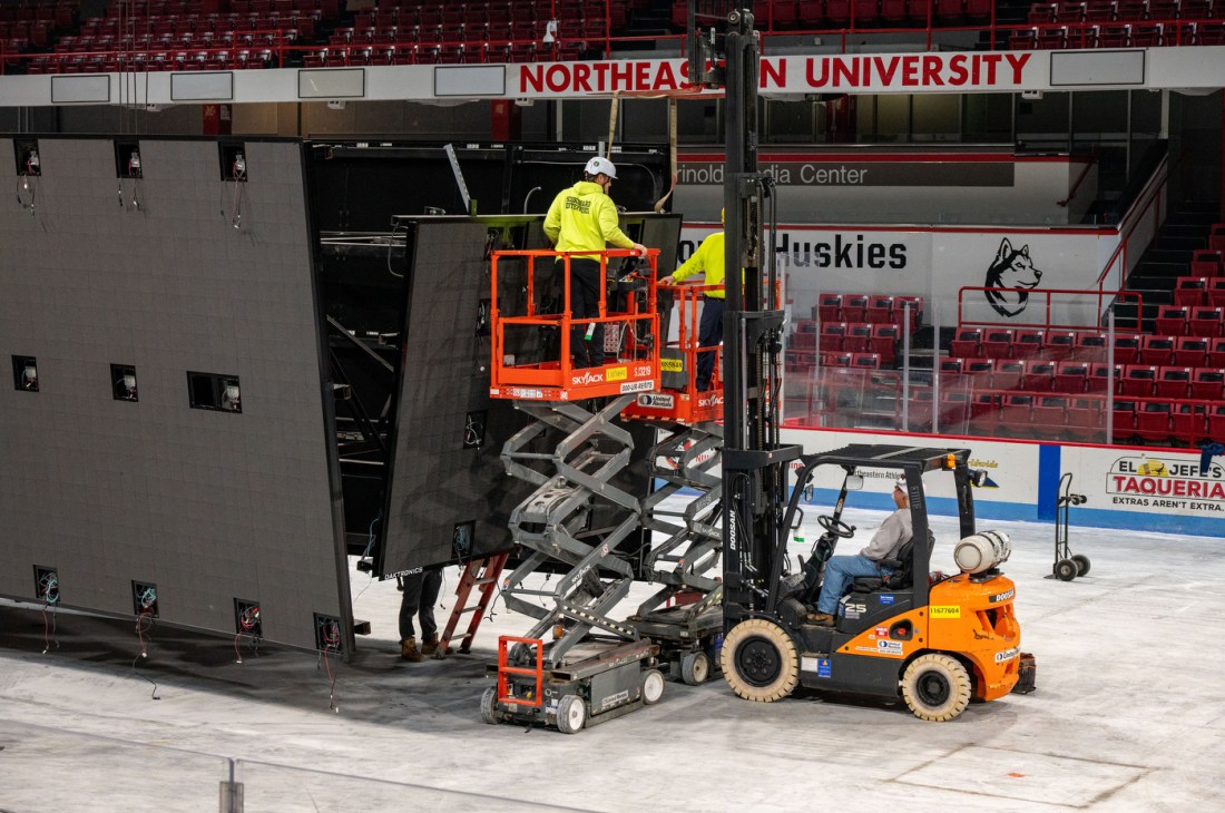 Workers in high vis yellow shirts and hard hats on orange risers working on deconstructing Matthews Arena from the inside.
