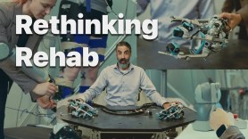 A person stands at a test. They're surrounded by robot hands and prosthetics. In the background, someone is adjusting a sensor on someone else's leg on a treadmill. Text in the image says 'Rethinking Rehab'