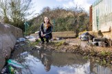 Woman at waste site surrounded by dumped rubbish