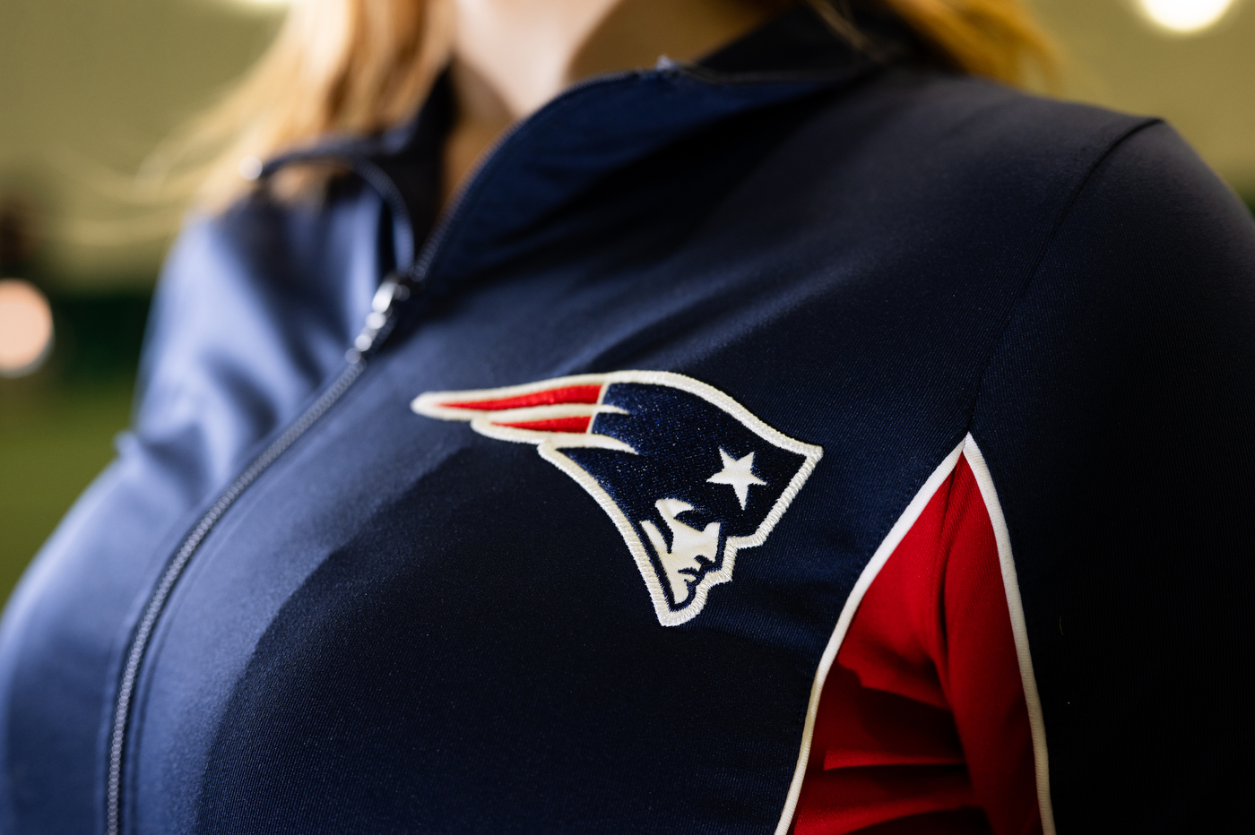 A closeup of the Patriots logo embroidered on the front of Lana's uniform