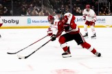 Two men's hockey players, standing parallel to one another, dressed in white and red jerseys.