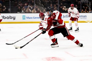 Two men's hockey players, standing parallel to one another, dressed in white and red jerseys.