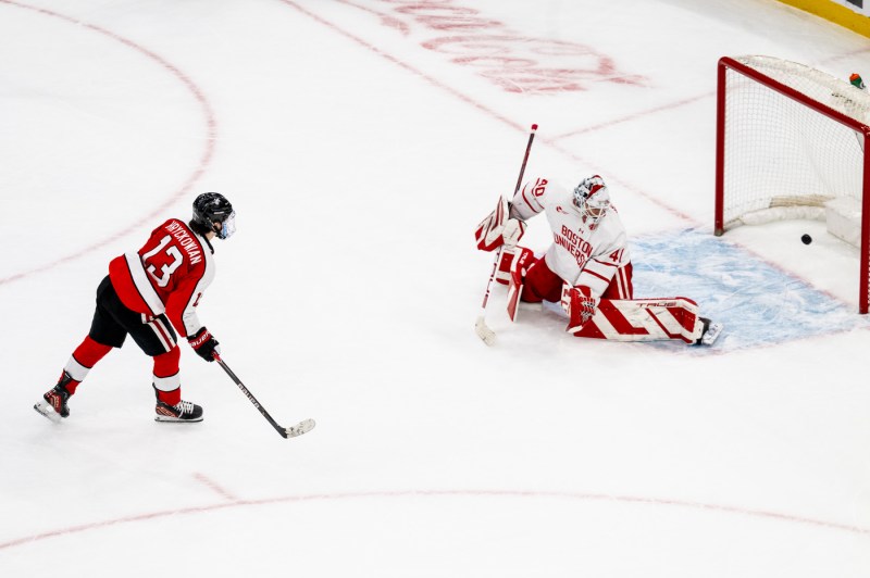 An action shot showing a Northeastern player scoring on the BU goalkeeper during a shootout.