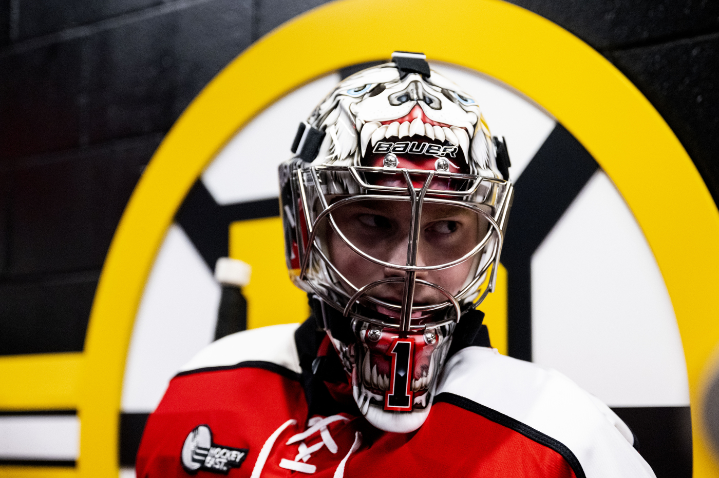 A Northeastern player shown against the Boston Bruins' logo.