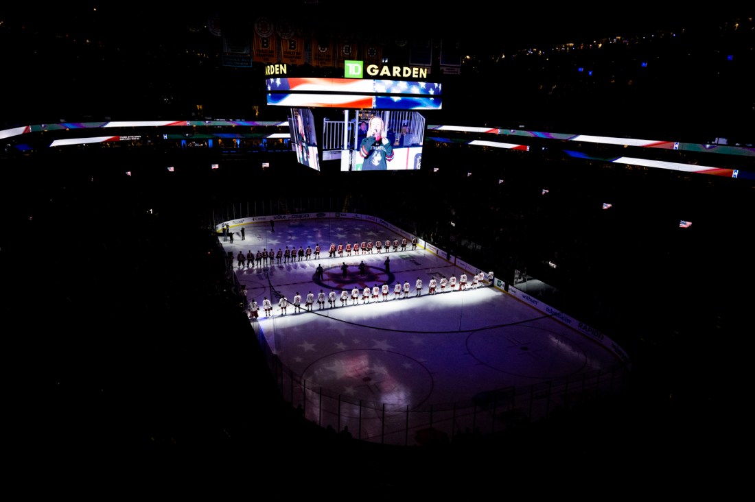 A far away wide shot of two hockey teams lined up to face off in TD Garden.