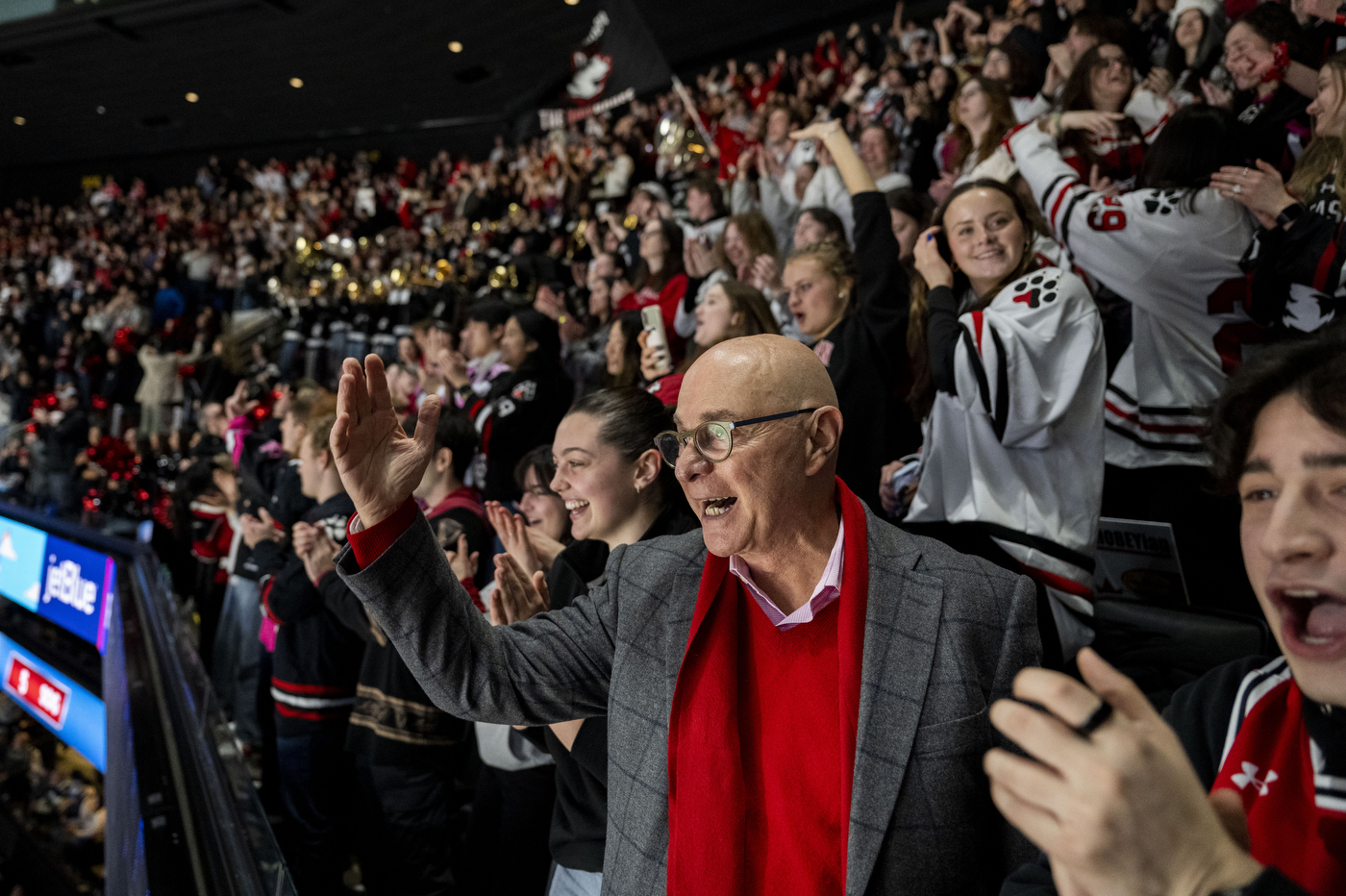 Joseph Aoun raises his hand and applauds amid a packed, jubilant crowd as Northeastern fans celebrate in the stands at TD Garden.