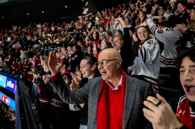 A crowd of Northeastern fans, including the university president, cheer on the men's hockey team.