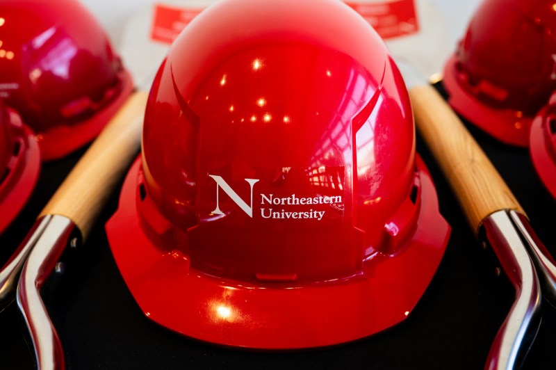 A close up of a red hard hat with the Northeastern University logo in white.