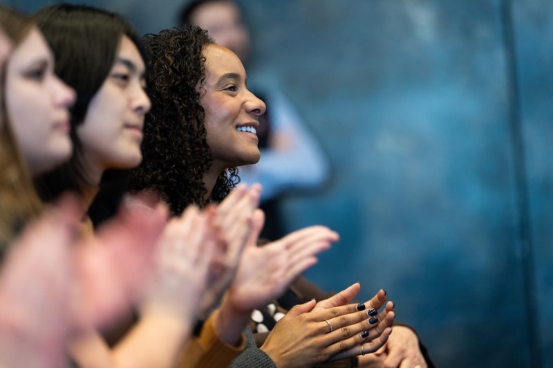 A close up of members of the crowd clapping.