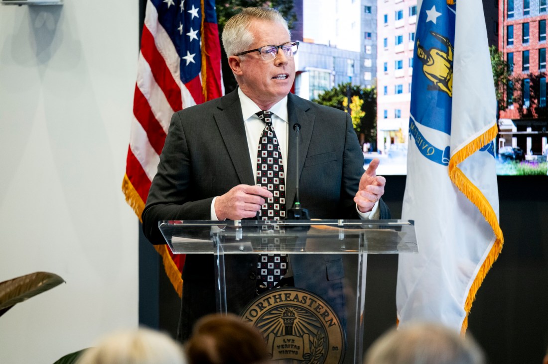 A person stands at a podium speaking into a microphone.