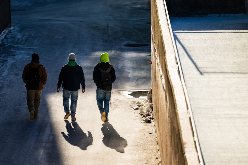 Three people backing the camera walk through the Boston campus.