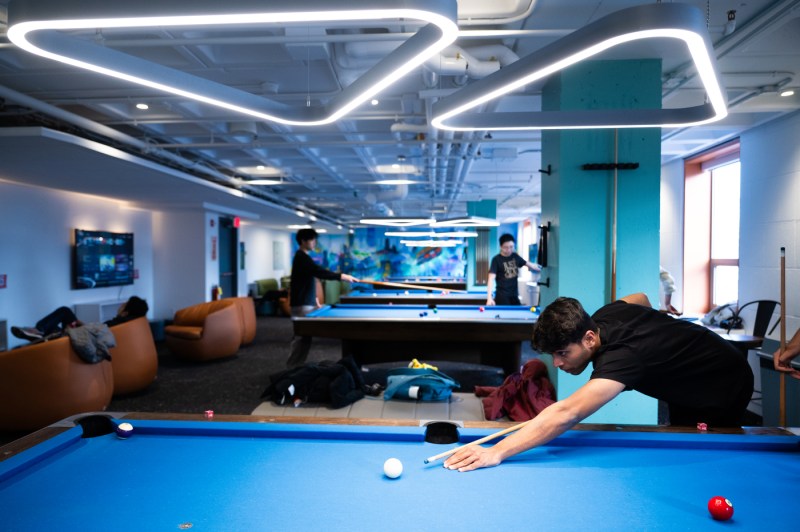 A shot of a students playing pool inside a student building.