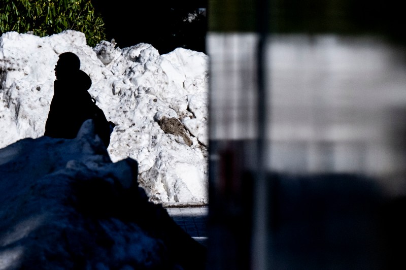 A student walks past a large snowbank. 