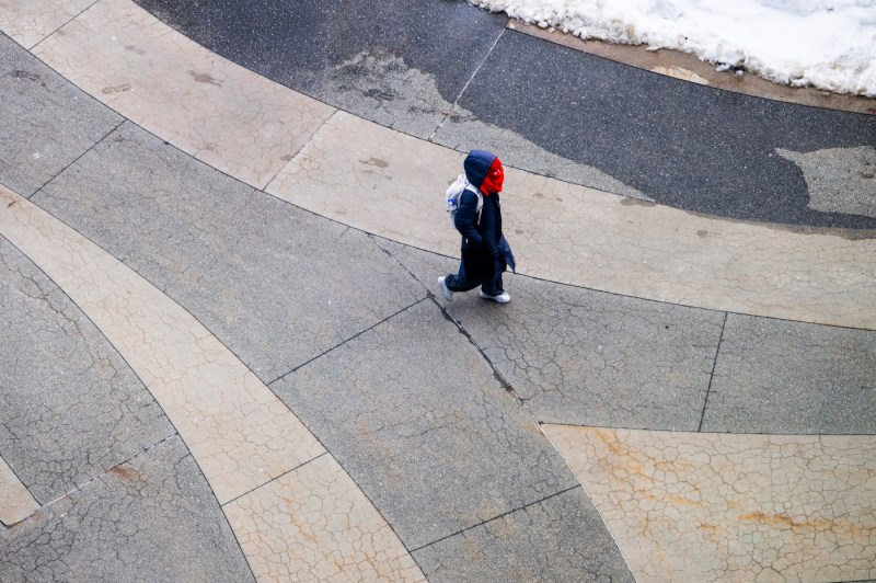 A person wearing winter gear walks on the ISEC terrace.