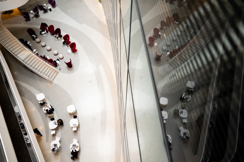 People sitting at tables and on armchairs in ISEC are seen from several floors above.