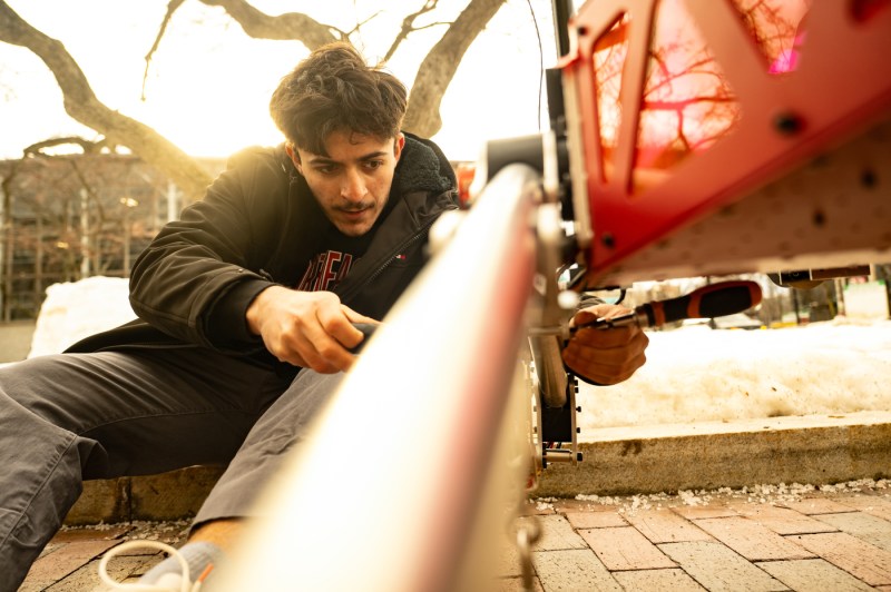 A student works on a robot outside. 