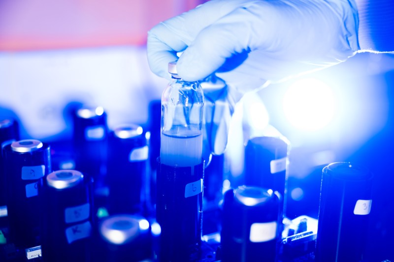 A gloved hands picks up a lab instrument.