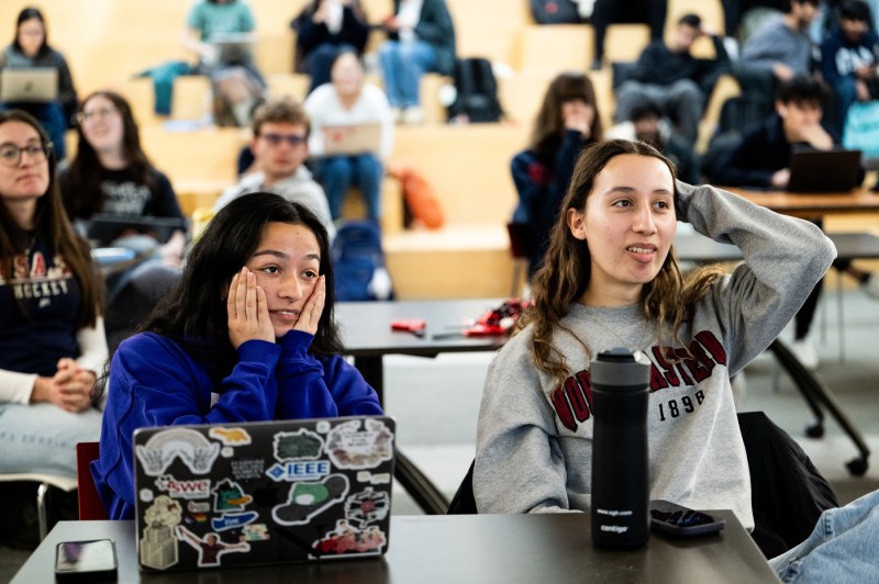 Two students sit at a table, visibly tense, as they watch the U.S. women's ice hockey gold medal match.