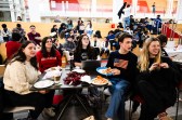 A group of students sit at a table for a watch party of the gold medal hockey game.