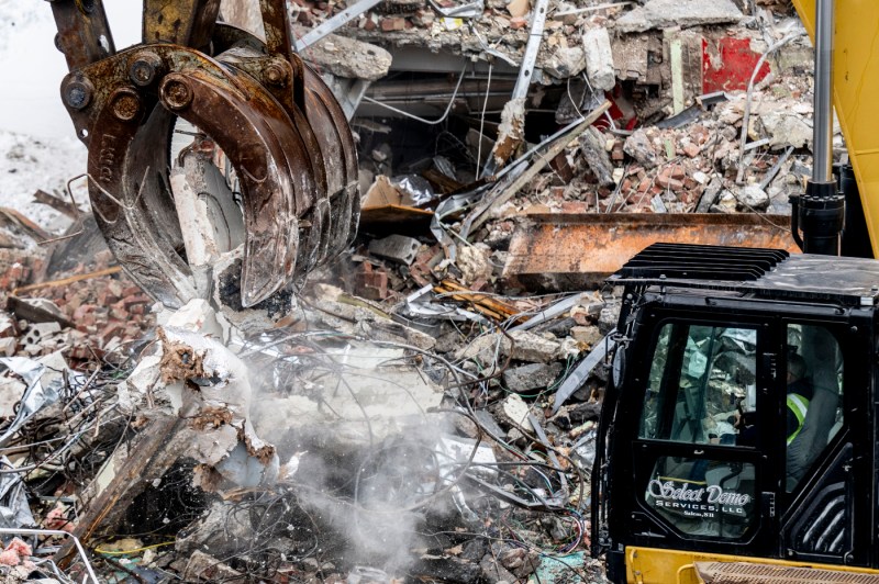 A close up of a construction vehicle as it works to bring down a building.