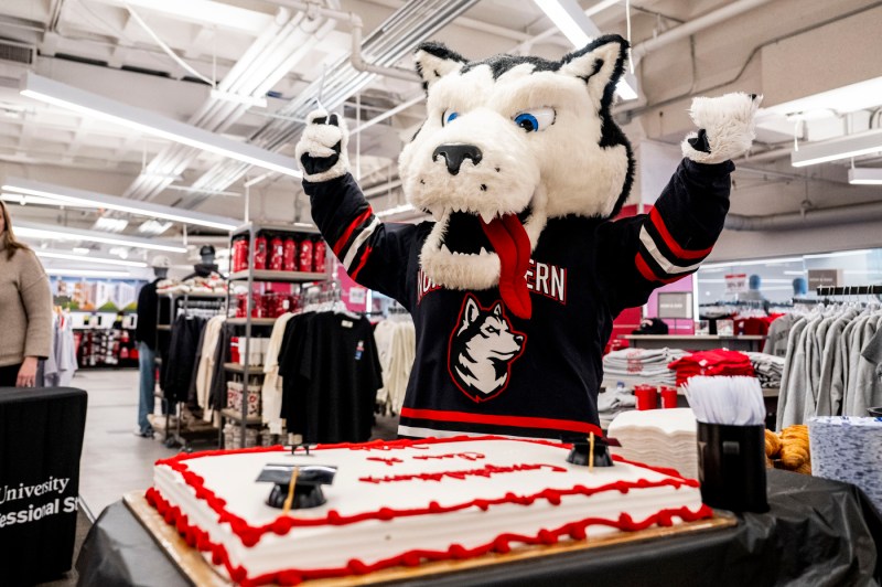 Paws the mascot poses with arms up for a photo during a fair held in the campus bookstore.