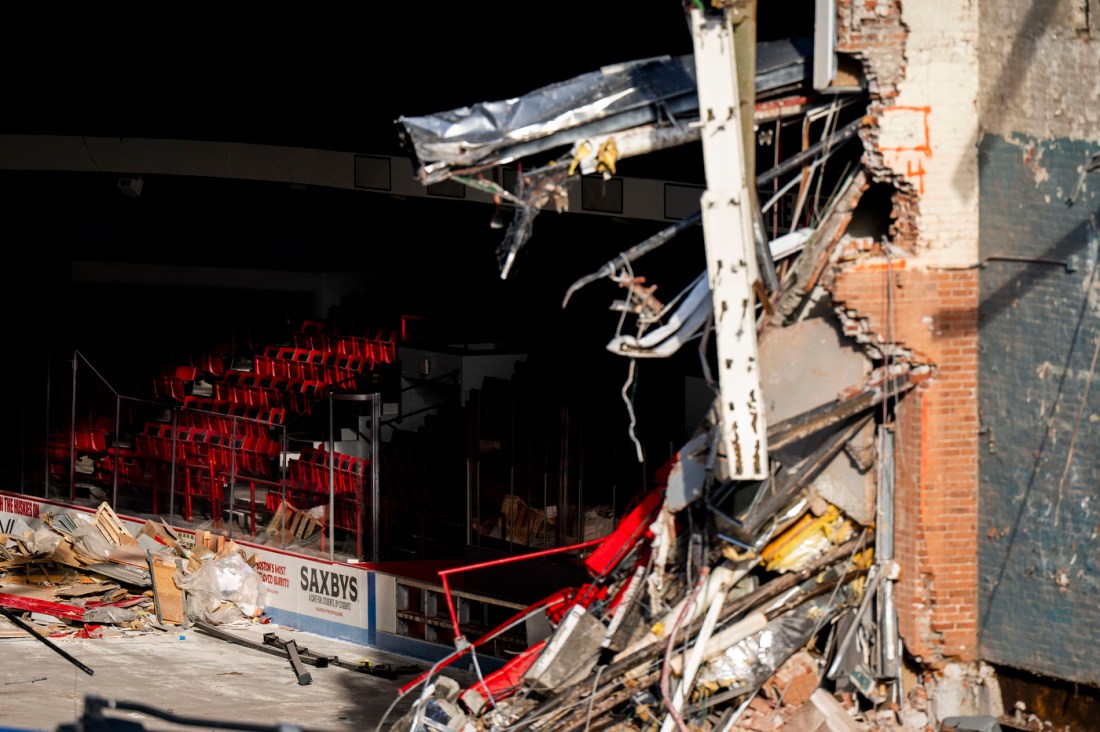 A close up of a partially torn down wall of the Matthews Arena, surrounding by debris.