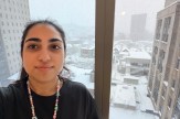 A co-op takes a selfie with a snowy urban view seen out the window in the background.