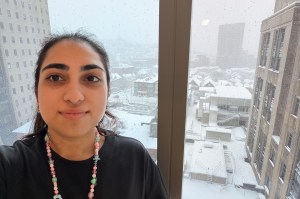 A co-op takes a selfie with a snowy urban view seen out the window in the background.