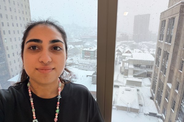 A co-op takes a selfie with a snowy urban view seen out the window in the background.