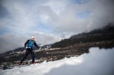 A man in a blue Olympics suit skies on the snow.