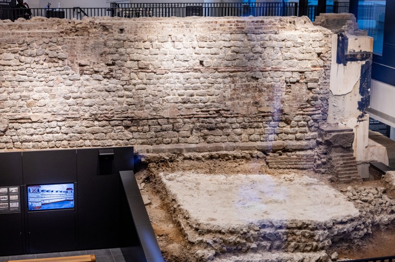 Ancient weathered stone ruins showing tiered rows of seating or steps arranged in horizontal layers, with visible aging and some vegetation growth.