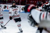 Alessia Baechler wearing a Northeastern hockey jersey and gear skating down a line of her teammates giving them fist bumps.