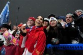 Eileen Gu poses in front of a group of fans at the Olympics with a medal around her neck.