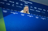Lindsey Vonn sitting at a press conference with Olympics branding on the backdrop and table she is sitting at.
