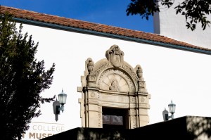 The outside of the Mills Art Museum in Oakland. The outside wall is bright white with an ornate arch around the entrance. There is an inscription 'Ars Longa, Vita Brevis' (Art is long, life is short).
