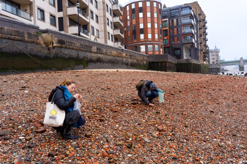 People collect items next to a river