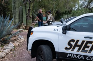 A Pima County Sheriff's deputy talks with a private security guard at Nancy Guthrie's home.