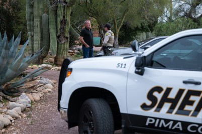A Pima County Sheriff's deputy talks with a private security guard at Nancy Guthrie's home.