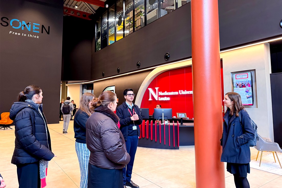 A tour group four people and a guide stands inside One Portsoken building by the reception desk.
