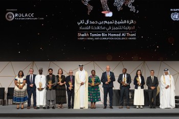 Nikos Passas standing on a stage in a row with other people.
